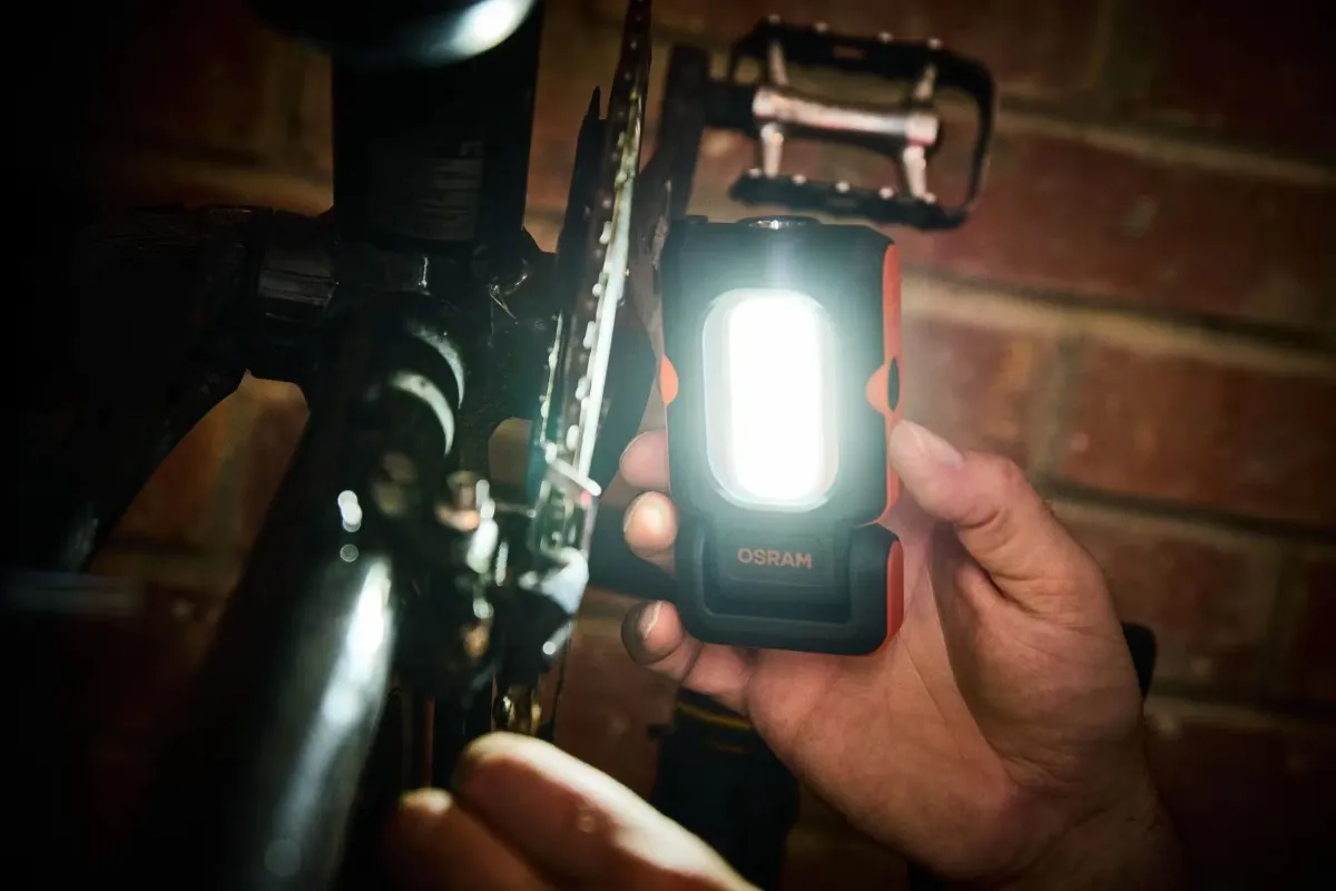 Użycie lampy jako latarki do oświetlenia mechanizmu łańcucha rowerowego w ciemnym pomieszczeniu.