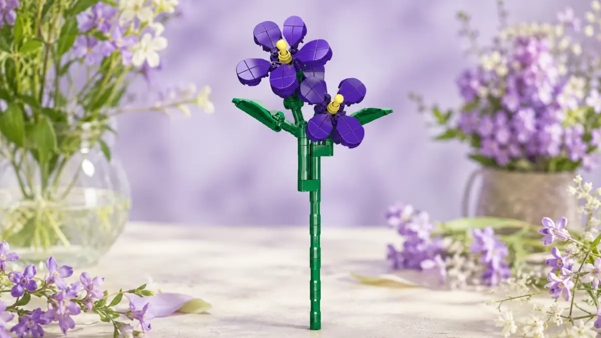 Flor violeta de blocos num caule verde, colocada entre flores em tons pastel.