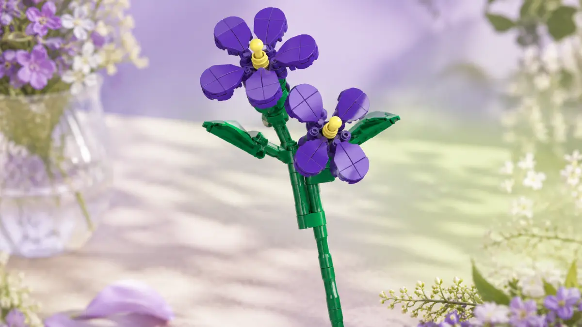 Flor violeta de blocos num caule verde, rodeada de flores numa composi&ccedil;&atilde;o pastel.