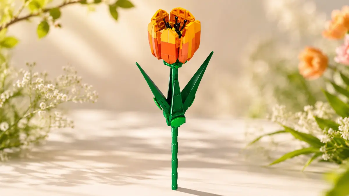 Flor laranja de blocos com caule e folhas verdes sobre um fundo claro e floral.
