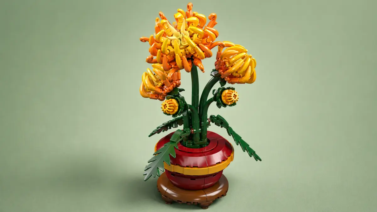 Modelo de flores laranja de blocos em um vaso vermelho sobre um fundo verde uniforme.