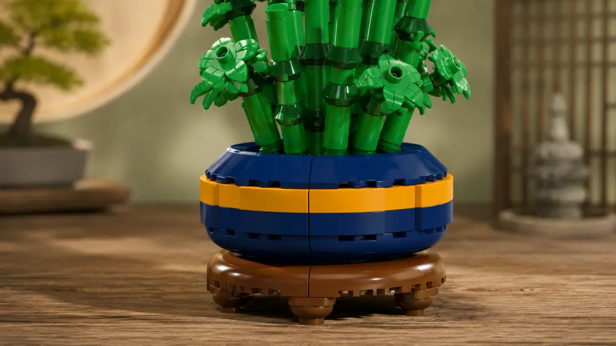 Vaso azul-marinho com faixa amarela e a parte inferior de um bambu de blocos verdes.