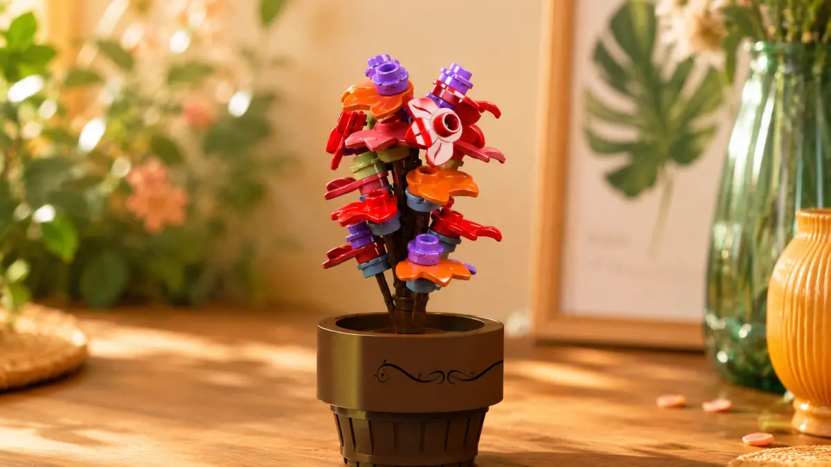 Flor colorida feita de blocos vermelhos, laranja e roxos num vaso castanho.