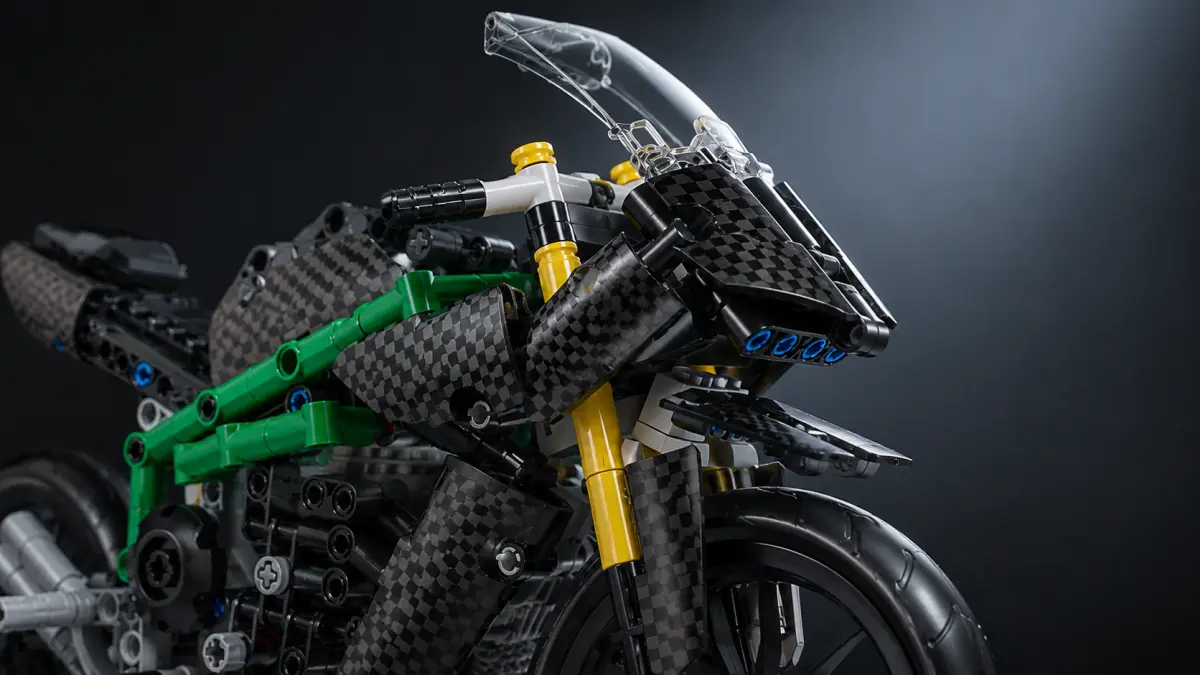 Nahaufnahme des vorderen Teils eines Motorrads aus Bausteinen mit Verkleidung, Lenker und goldenen Stoßdämpfern.
