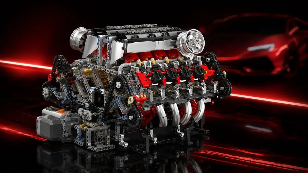 Modello in mattoncini di un motore V8 su sfondo nero con scie di luce rosse e la sagoma di un'auto