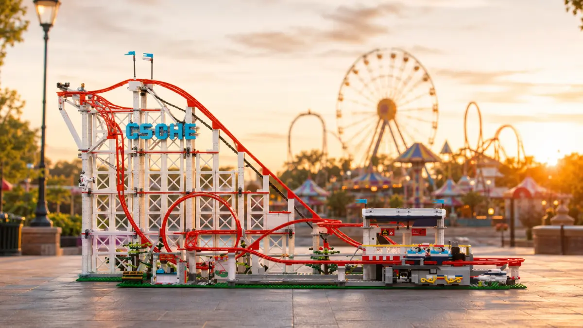 Gün batımında eğlence parkı arka planında kırmızı raylı blok roller coaster