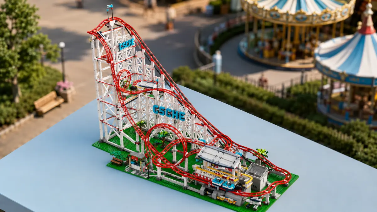 Yeşil taban üzerinde bloklardan yapılmış roller coaster, parkta bir dönme dolap eşliğinde üstten görünüm