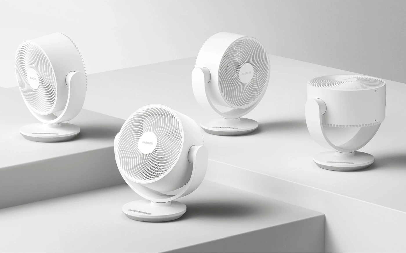 Cuatro circuladores Xiaomi blancos colocados en distintos ángulos sobre escalones, mostrando el rango completo de ajuste del cabezal