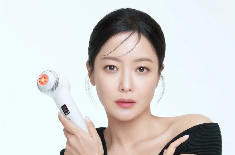 Mulher segurando perto do rosto um dispositivo cosmético branco Age-R Ultra que emite luz vermelha.
