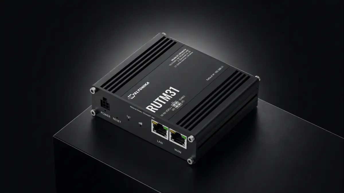 Roteador industrial preto sobre uma base, com portas LAN e WAN e conector de alimentação na frente.