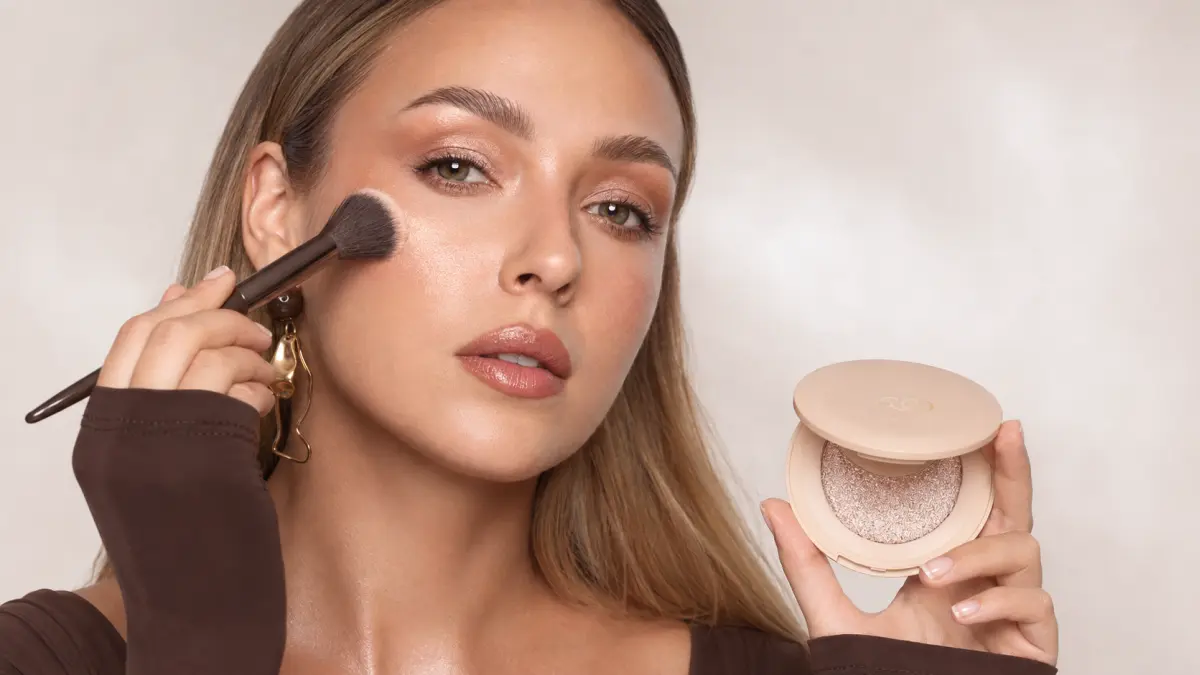 Модель наносит кистью LOVRO Wet Glow на скулу и демонстрирует открытую упаковку